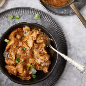 chicken and sausage gumbo in a black bowl with a spoon.
