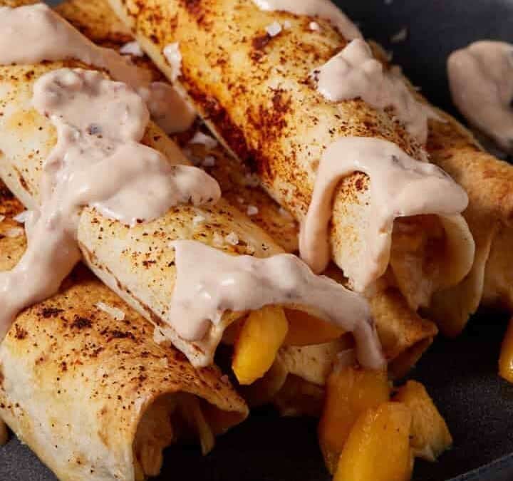 Taquitos drizzled with a yogurt sauce.
