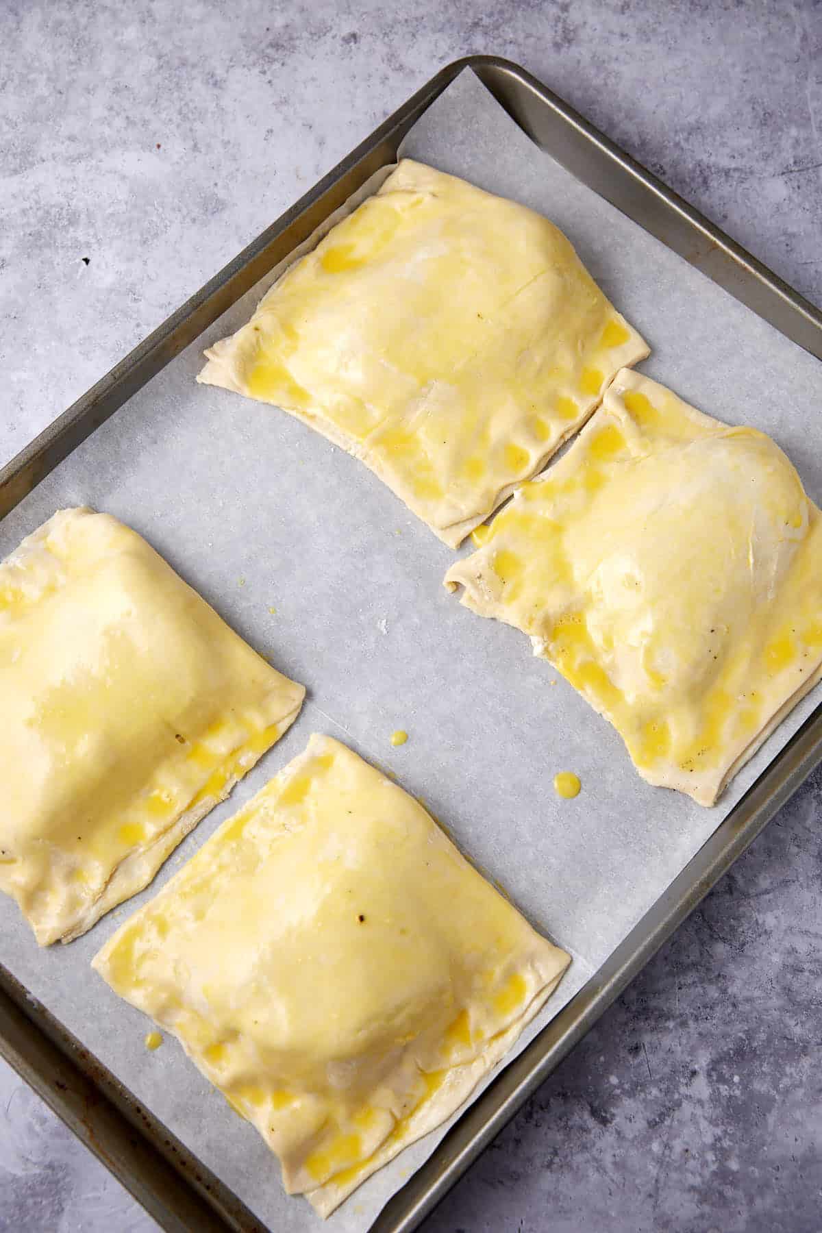 chicken in puff pastry on a baking sheet brushed with egg wash.