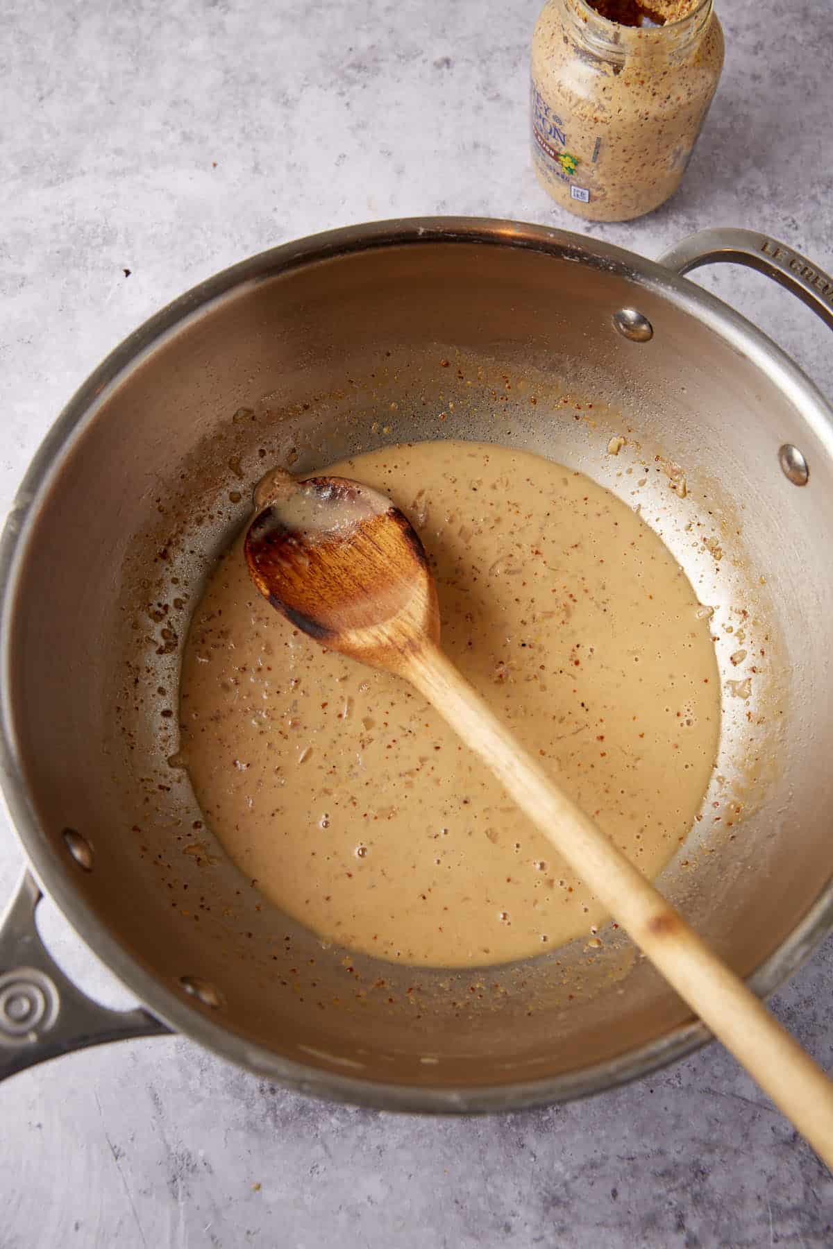 mustard cream sauce in a saucepan with a wooden spoon.