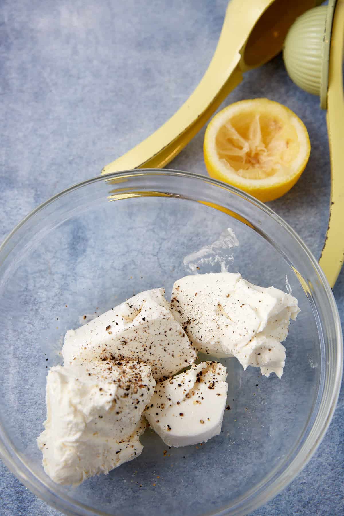 glass bowl with goat cheese, cream cheese, lemon juice, salt, and pepper.
