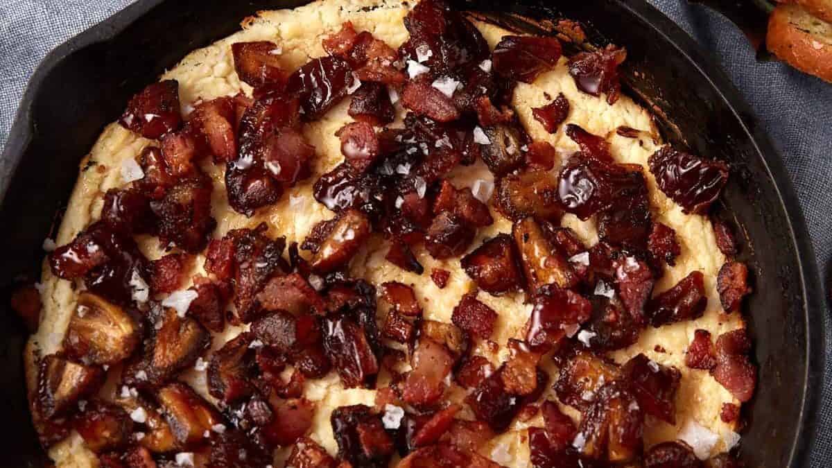 goat cheese dip in a cast iron skillet on a gray background.