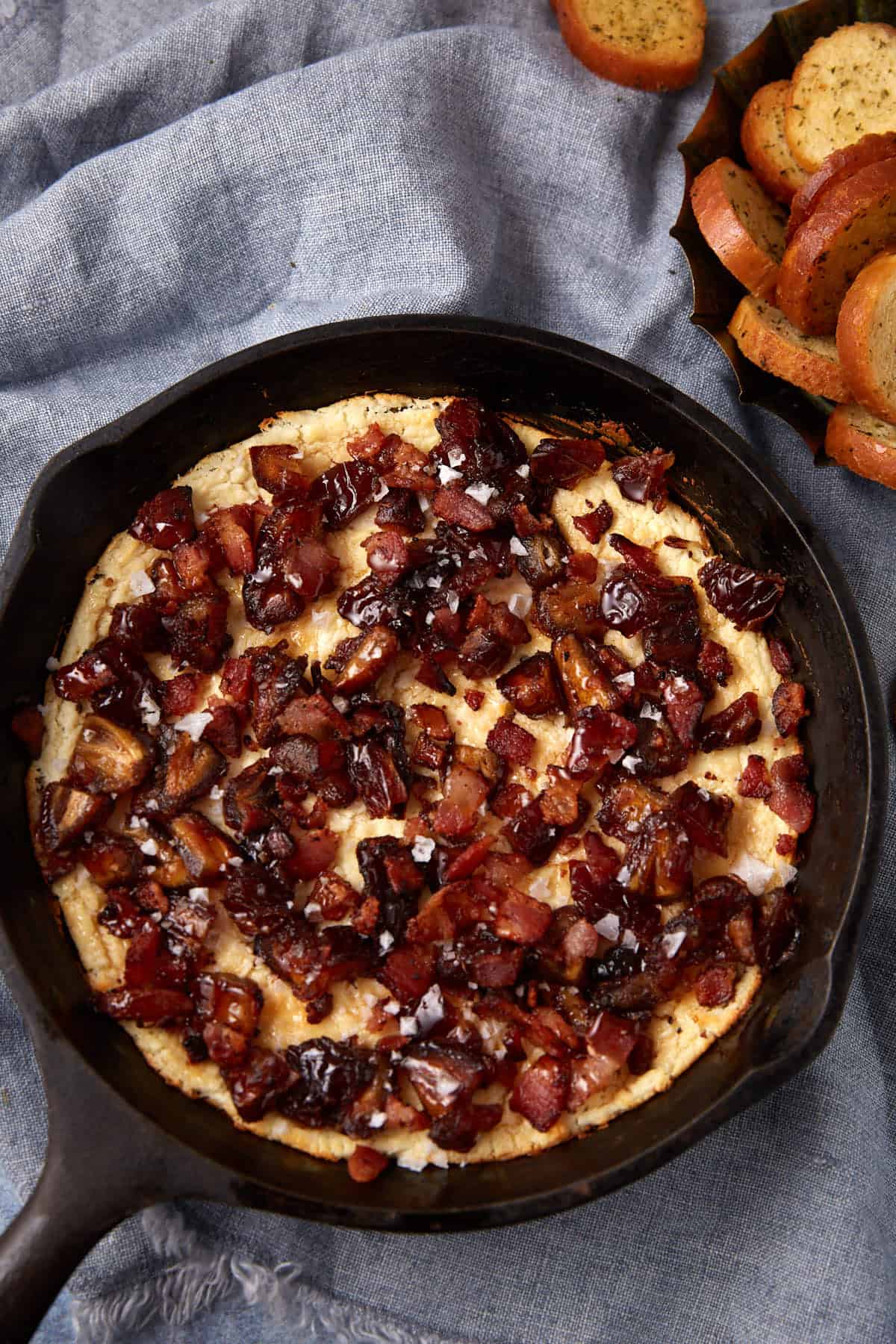goat cheese dip in a cast iron skillet on a gray background.