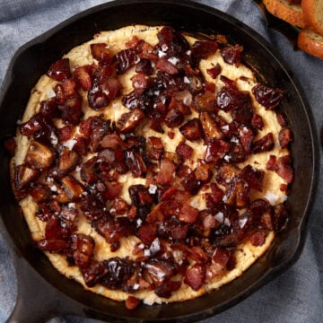 goat cheese dip with dates, bacon, and hot honey in a cast iron skillet.