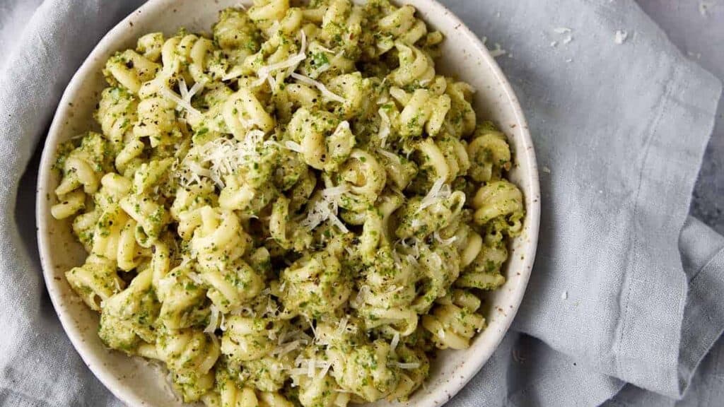 A side dish of pesto pasta next to fresh parsley.
