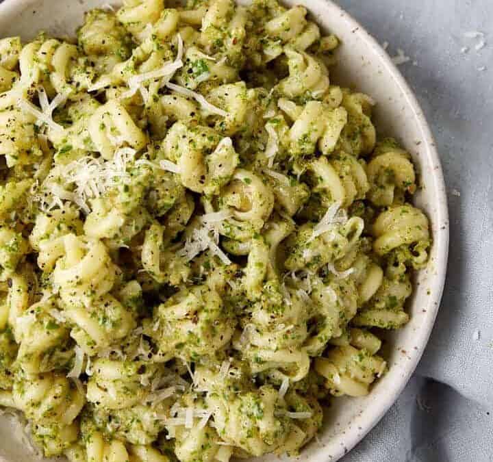 A side dish of pesto pasta next to fresh parsley.