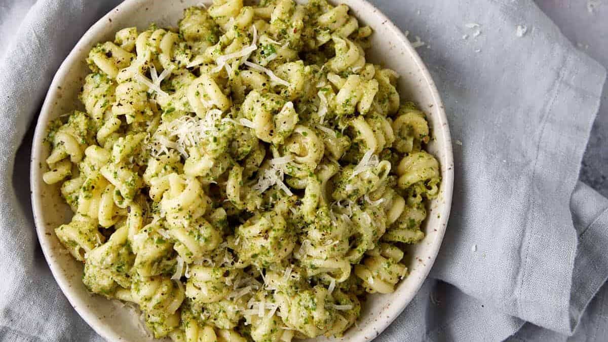 A side dish of pesto pasta next to fresh parsley.