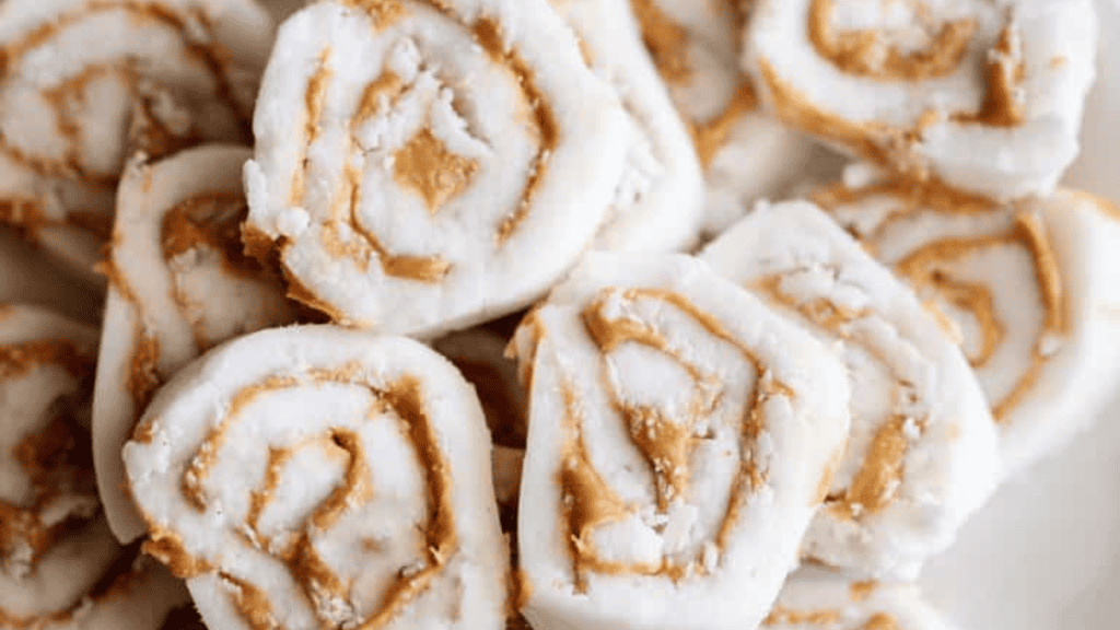 Close-up of several pieces of white pinwheel candy with a creamy peanut butter swirl inside, arranged on a white surface—a delightful treat often found in classic Irish recipes.