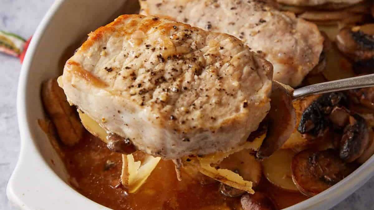 A casserole dish with baked pork chops and potatoes.