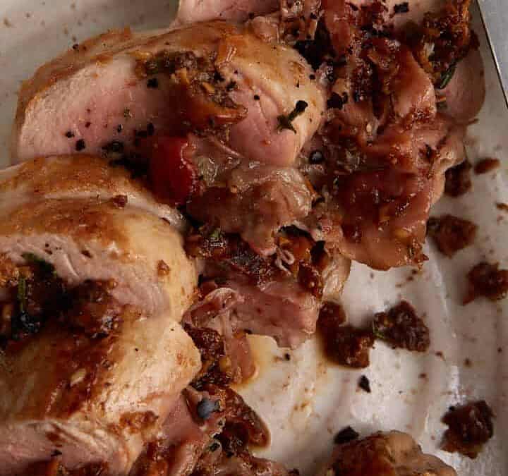 A platter of sliced pork tenderloin with a knife.