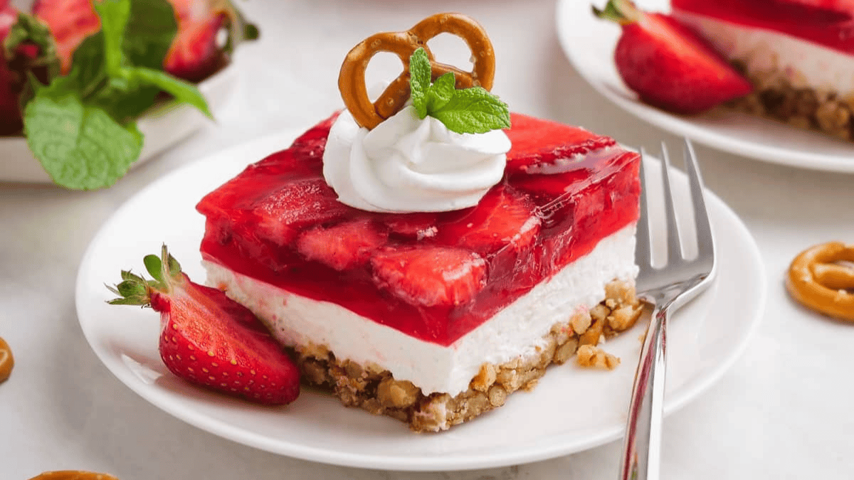 A slice of strawberry cheesecake with a pretzel on top.