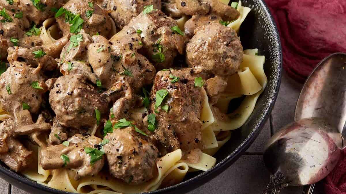 A bowl of stroganoff meatballs with egg noodles.
