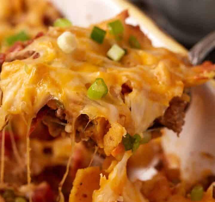 A spoon removing a scoop of cheesy taco casserole.