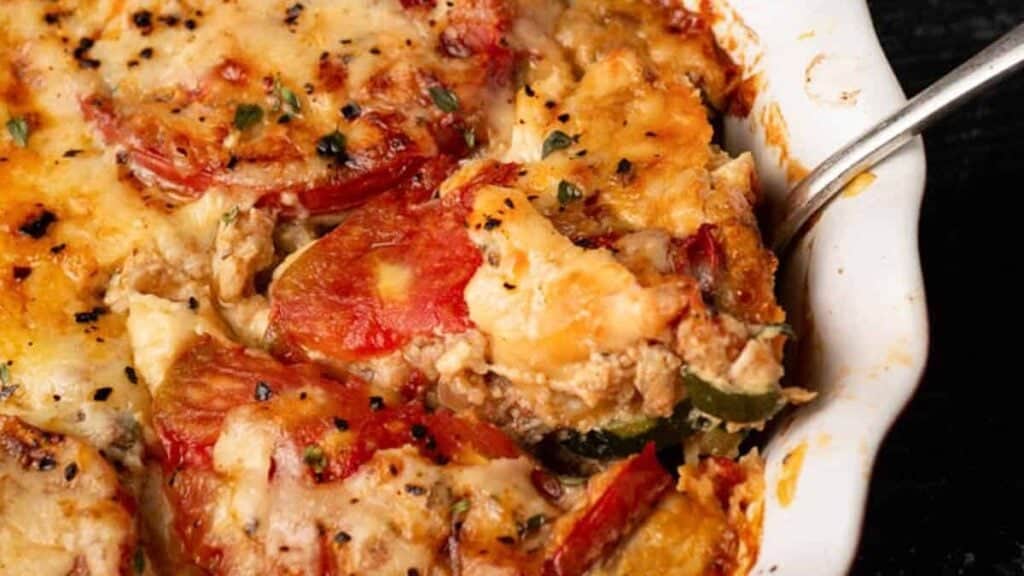 A baking dish of tomato pie with a serving spoon.