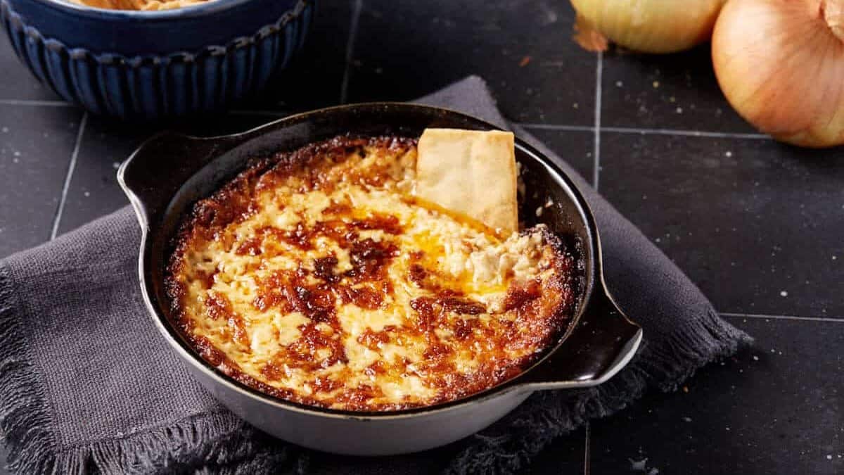 A pita chip in a bowl of onion dip.