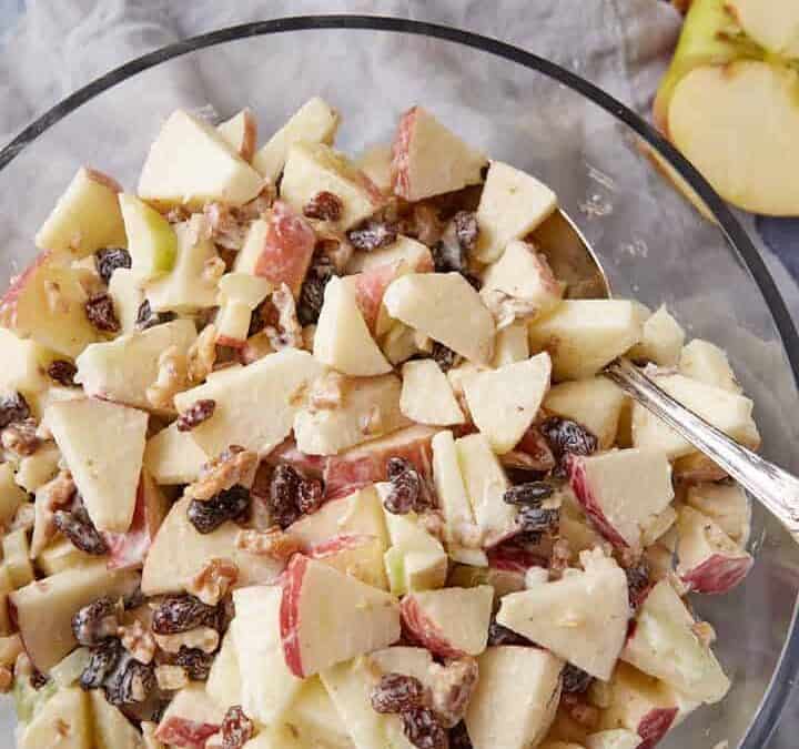 A bowl of apple salad with a serving spoon.