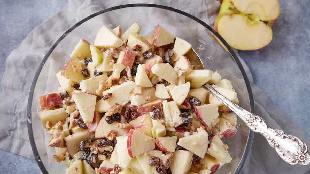 A bowl of apple salad with a serving spoon.