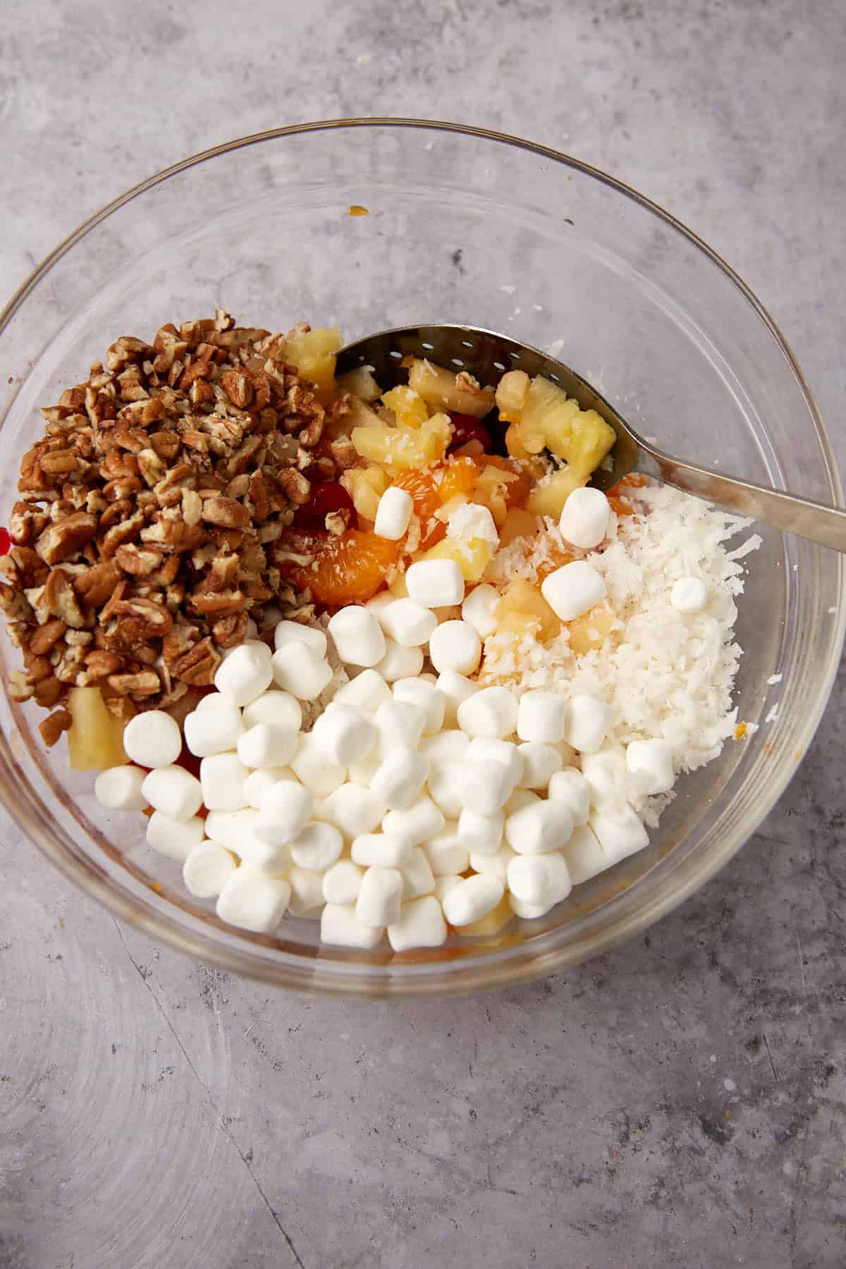 pecans, marshmallows, coconut, and fruit in a glass mixing bowl.