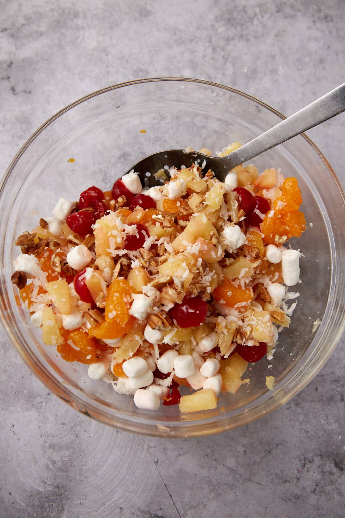 mixed fruit, nuts, and coconut in a glass mixing bowl.