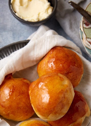 buttermilk yeast rolls on top of a towel on a plate.