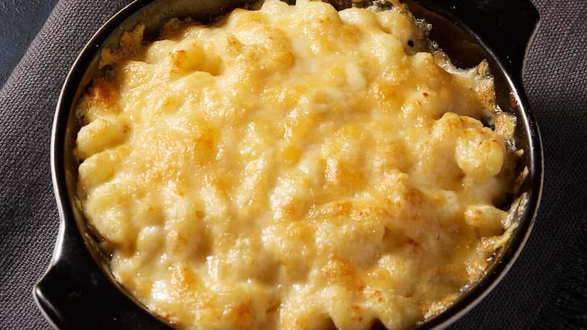 Baked macaroni and cheese in a round baking dish on a napkin with spoons.