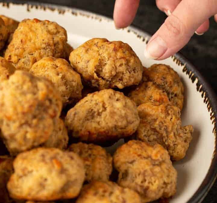 A sausage ball being taken from a platter.