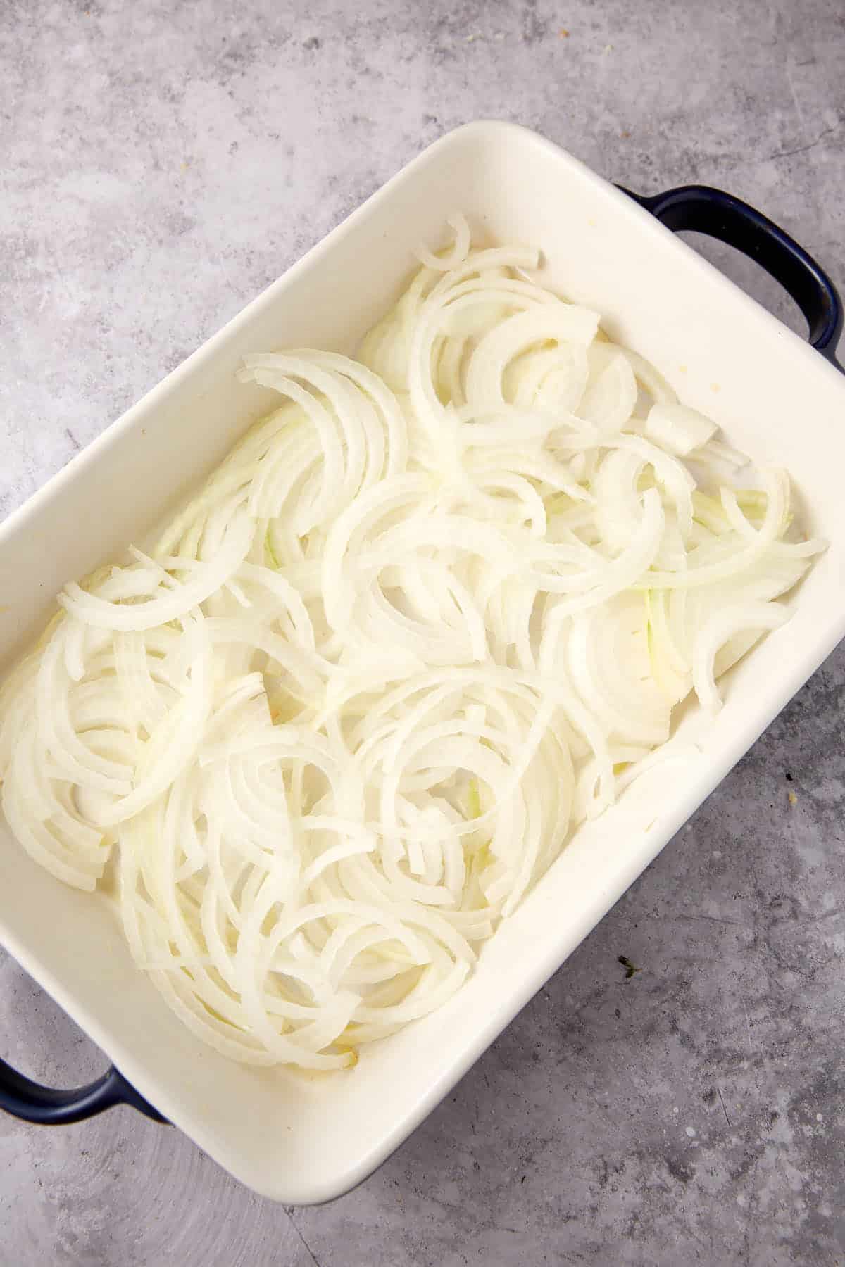 sliced onions in a baking dish.
