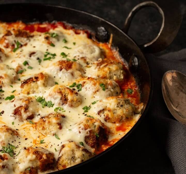 A skillet of parmesan chicken meatballs after it has been baked.