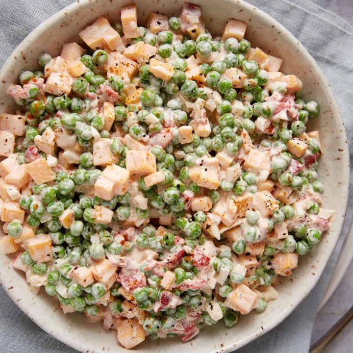 A pea salad with cheddar cheese in a serving bowl.