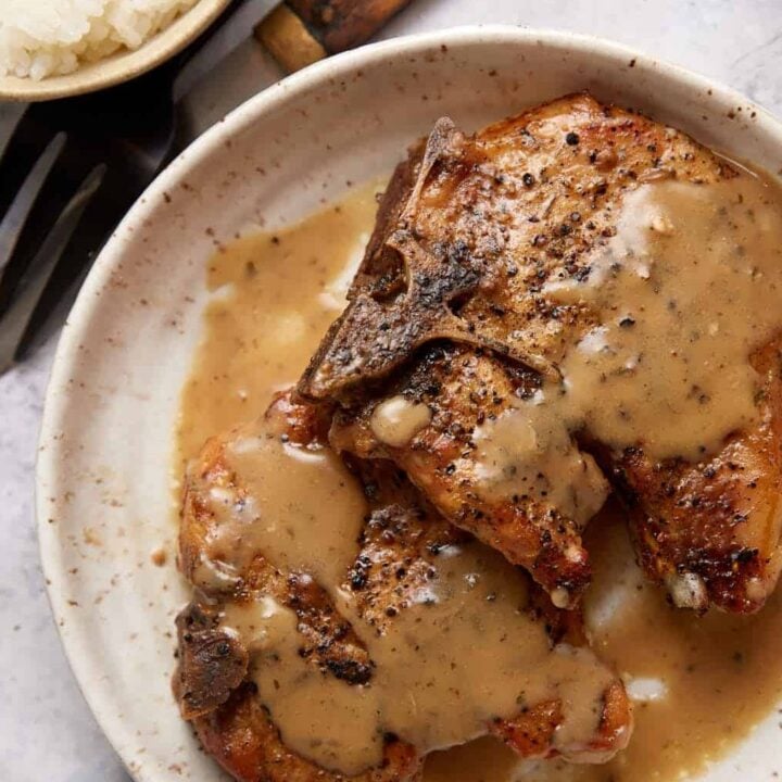 Pork chops on a plate covered with ranch gravy.