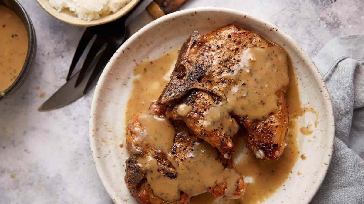 Pork chops on a plate covered with ranch gravy.