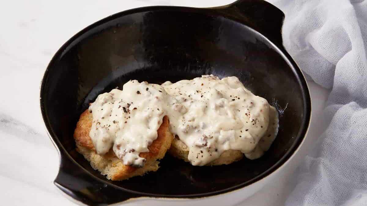 A casserole dish with a biscuit covered in sausage gravy.