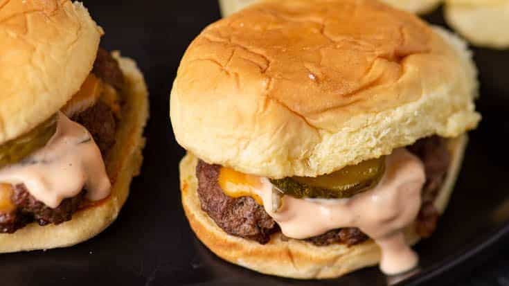 Two burgers on a platter with chips