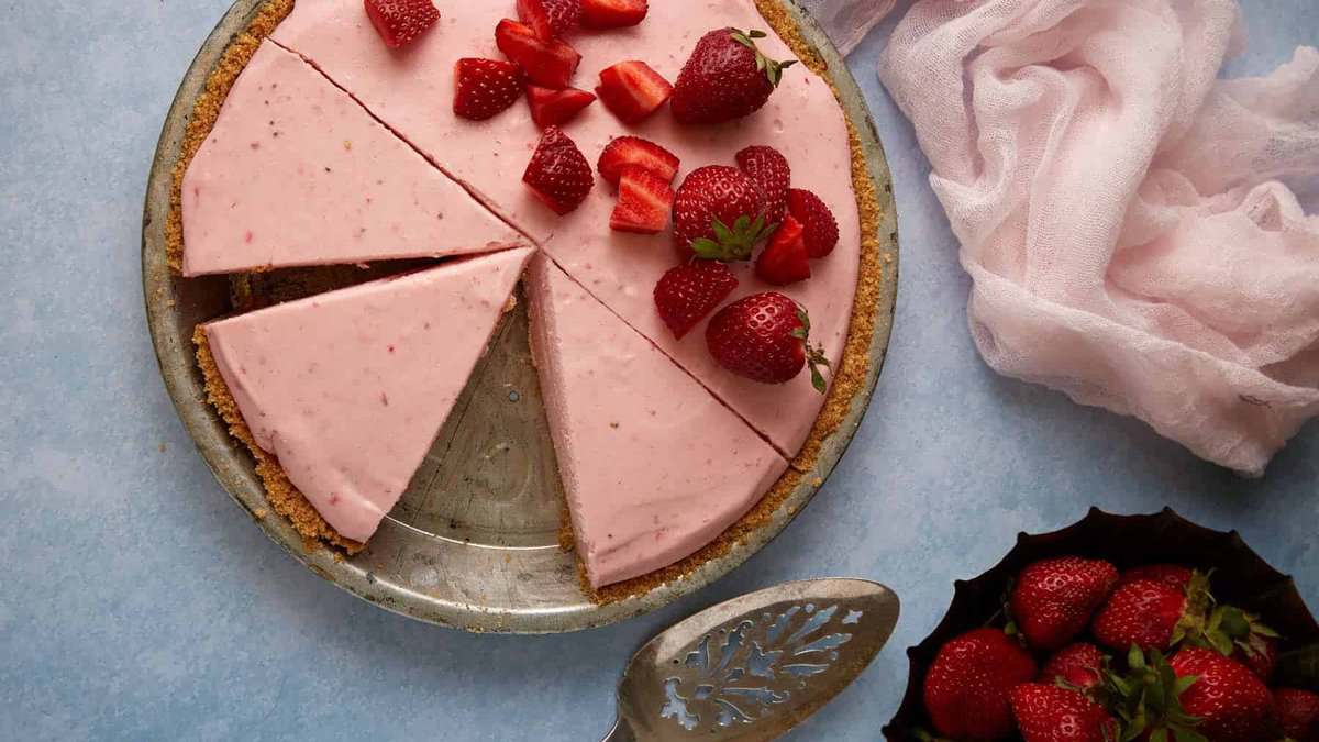 A strawberry pie in a pie plan with cut strawberries on top