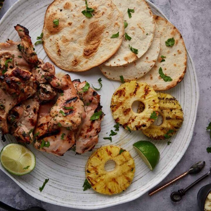 Grilled chicken thighs on a patter with grilled pineapple.