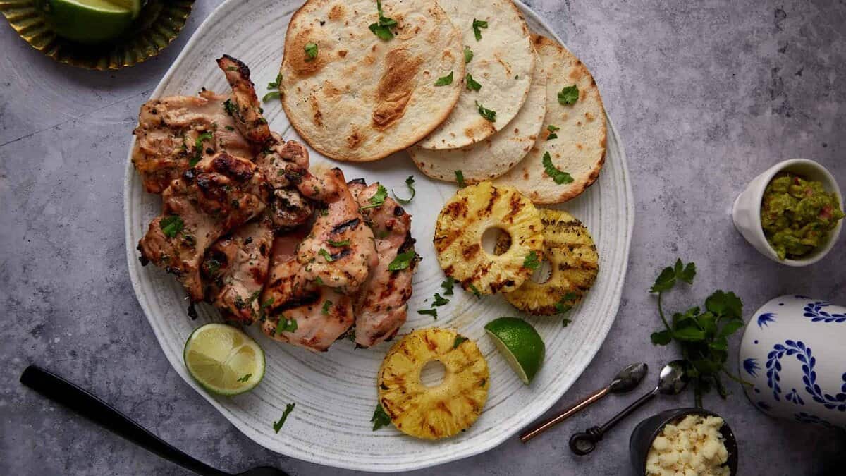 Grilled chicken thighs on a patter with grilled pineapple.