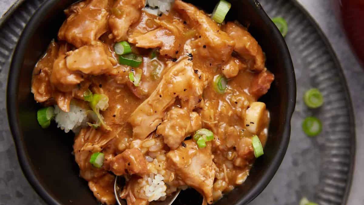 A plate of chicken gumbo over rice with a spoon.