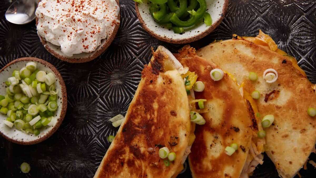 Three quesadillas next to toppings.
