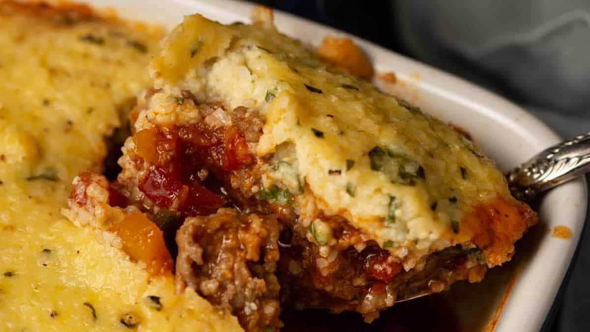 A casserole dish of chili topped with cheesy grits.