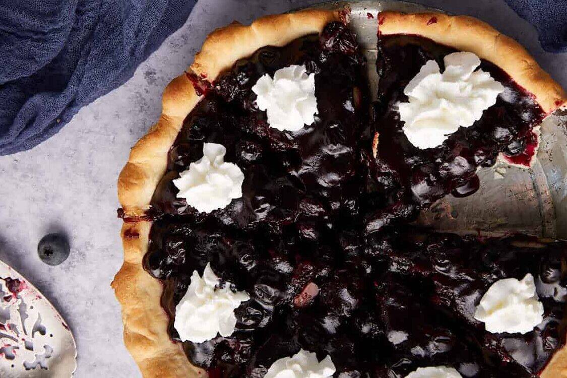 A blueberry pie next a pie server.