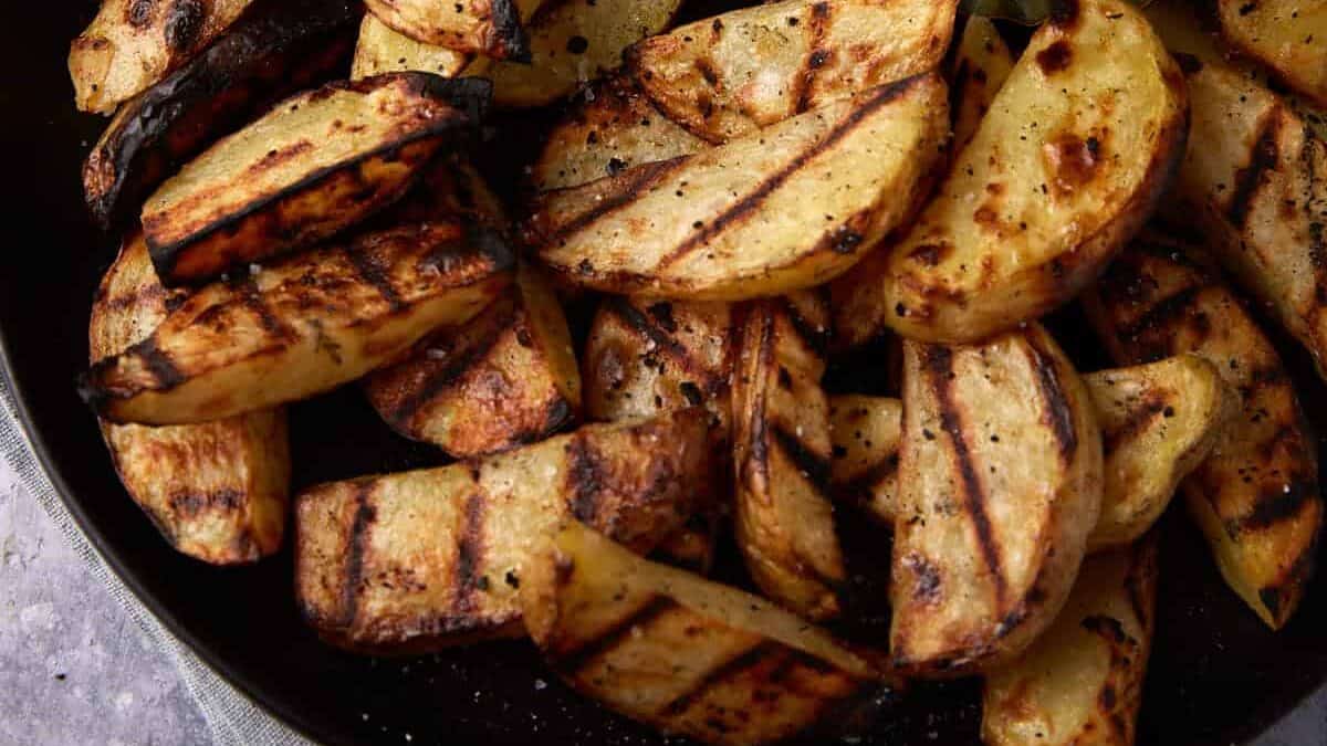 A platter of grilled potatoes next to a dish of aioli.