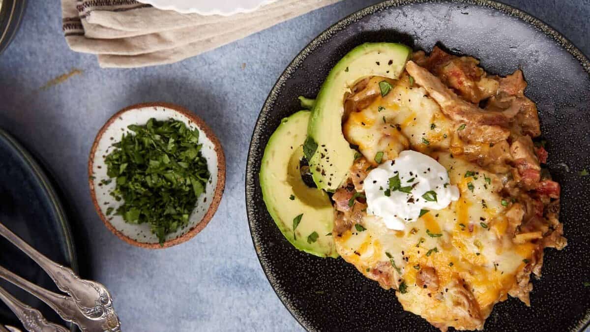A serving of king ranch casserole with a sliced avocado.
