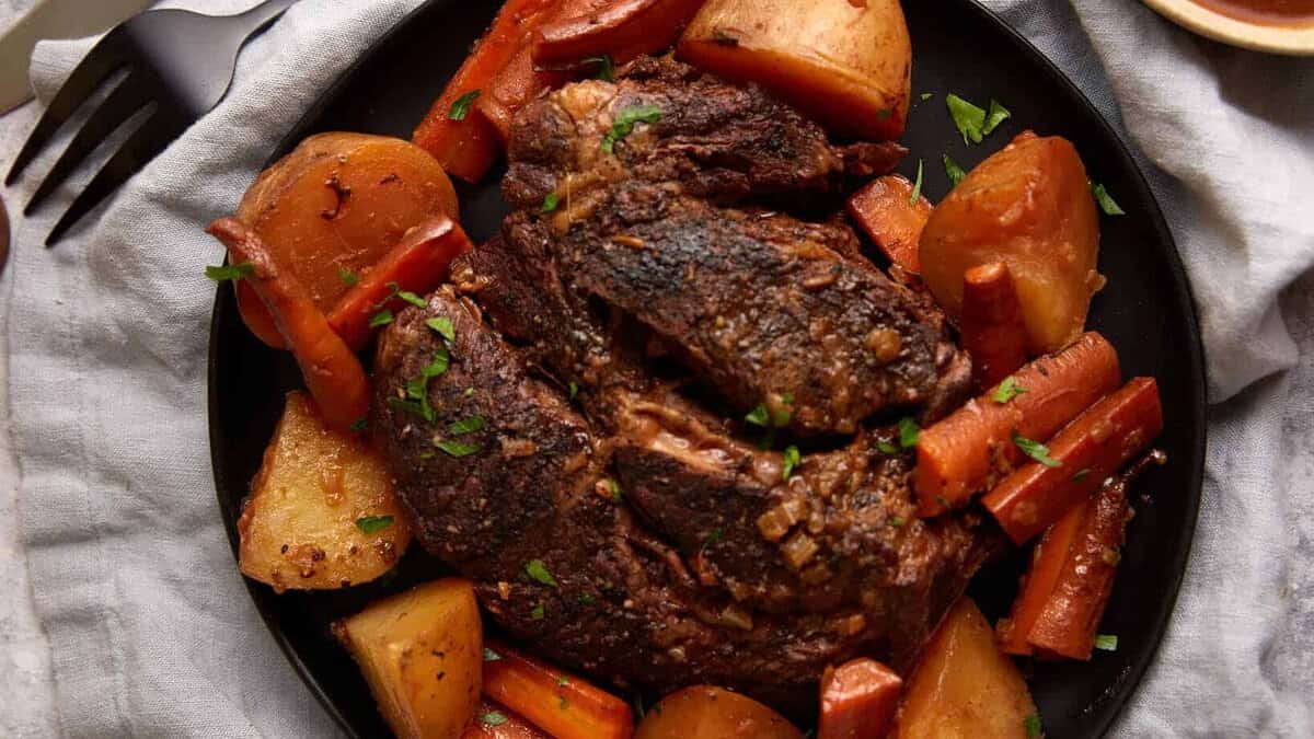 A platter of roast beef with carrots and potatoes.
