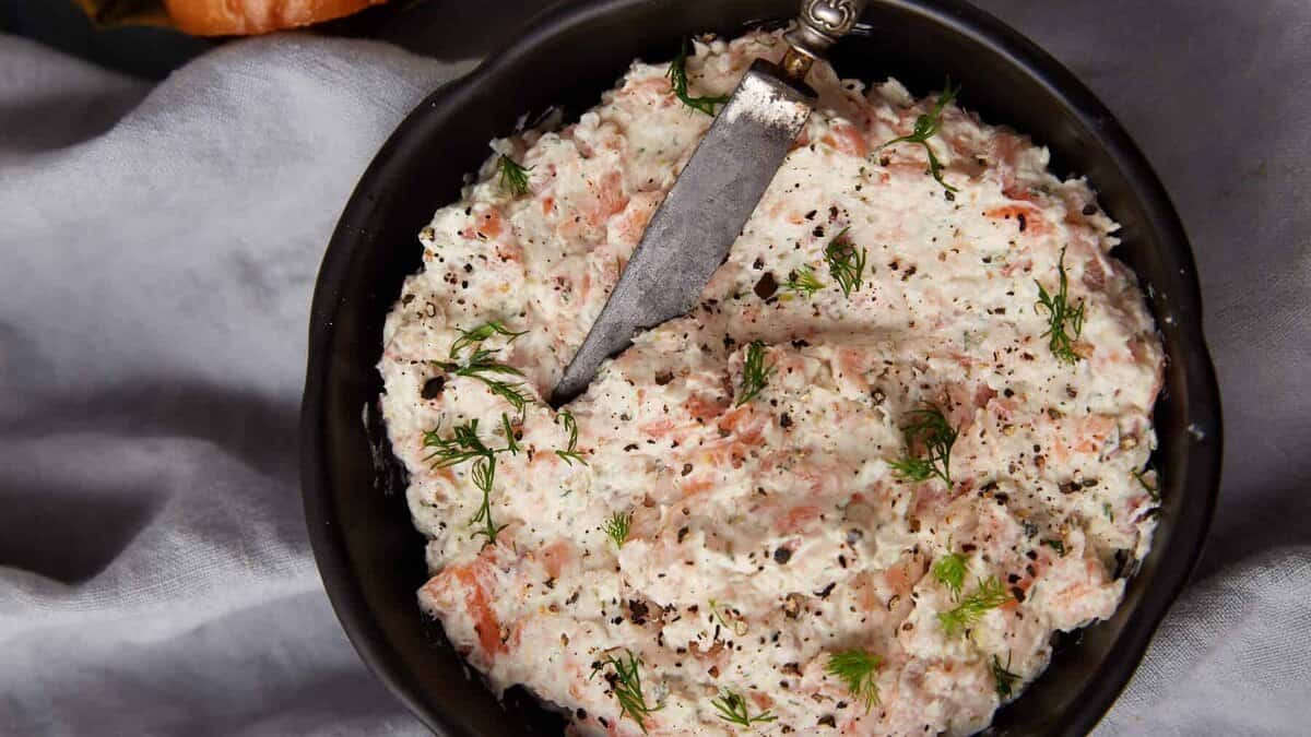 A bowl of salmon dip with a small knife.