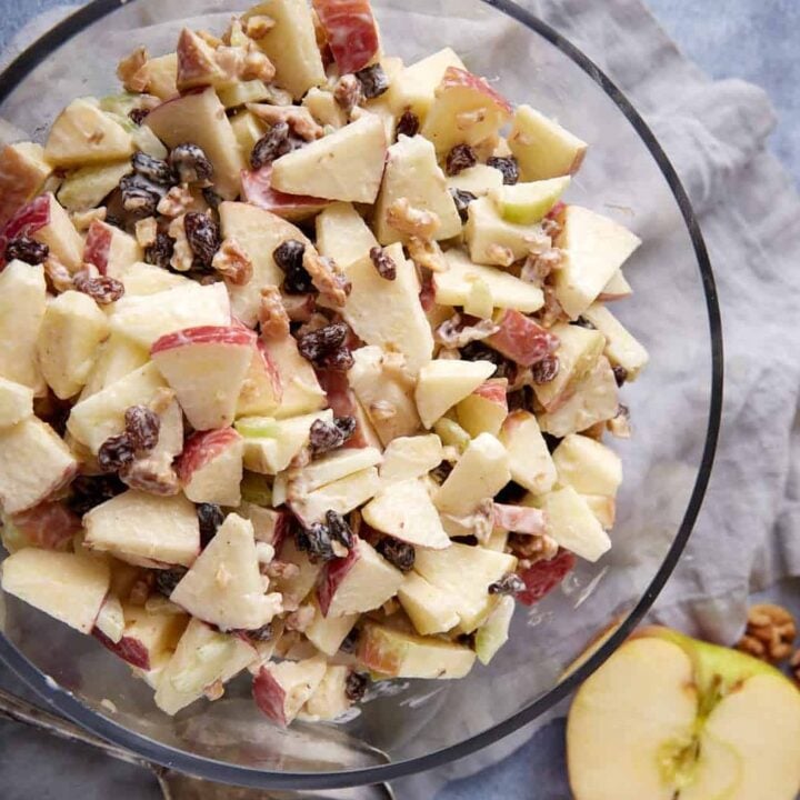 A bowl of apple salad with a serving spoon next to it.