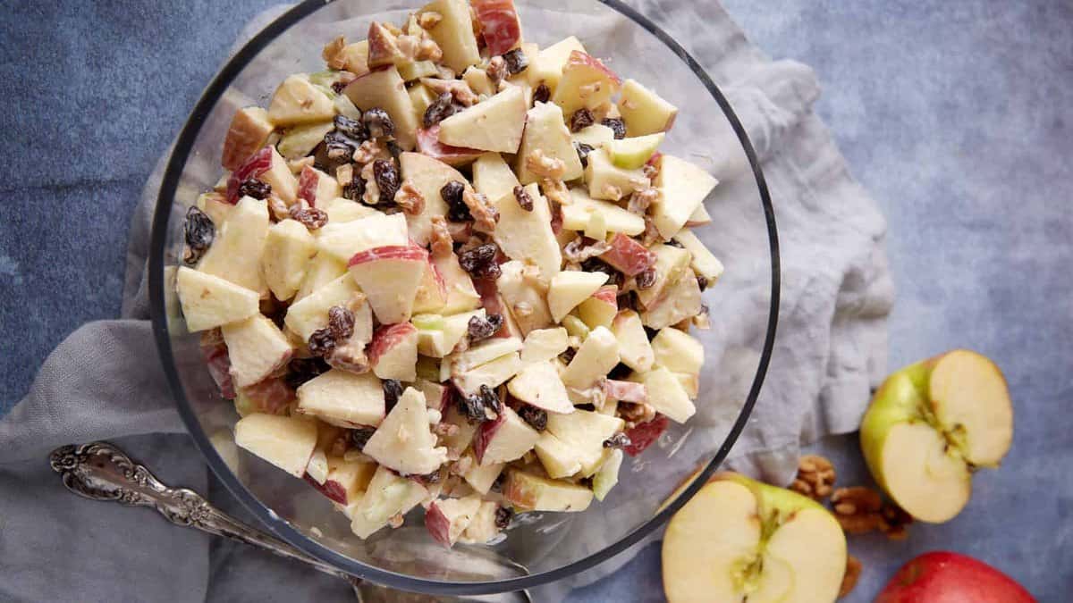 A bowl of apple salad with a serving spoon next to it.