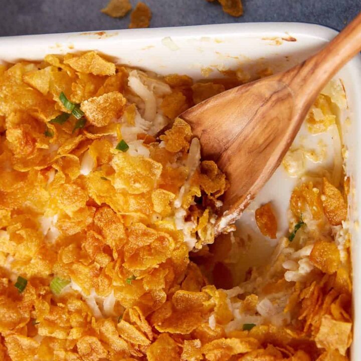 A chicken and hashbrown casserole with a wooden spoon.