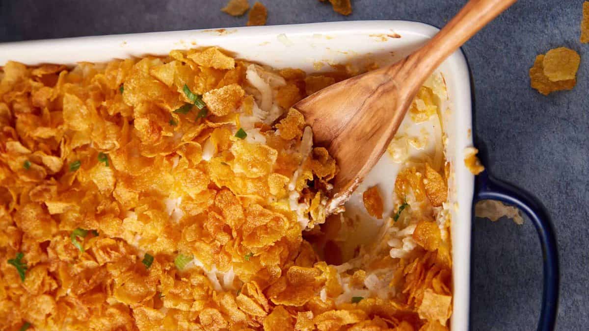 A chicken and hashbrown casserole with a wooden spoon.