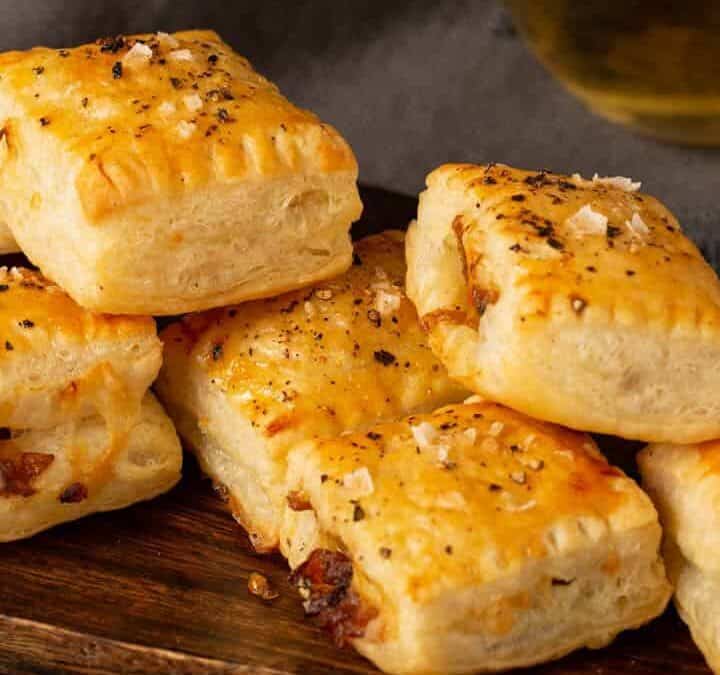 French onion pastry bites on a platter with a glass of wine.