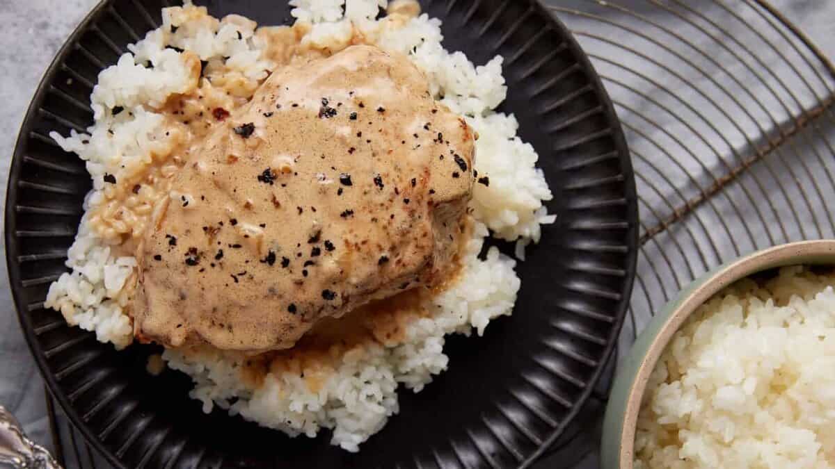 A plate with a pork chop over rice.